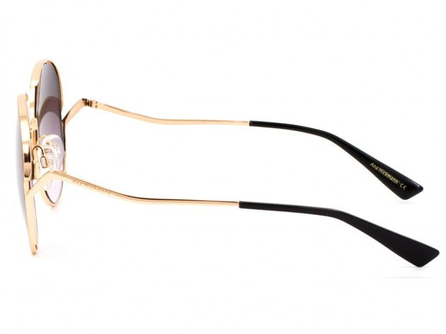 Round Ana Hickmann sunglass with a gold metal frame, gold metal wavy temples with black acetate ends and grey graduated lenses. Left full view.